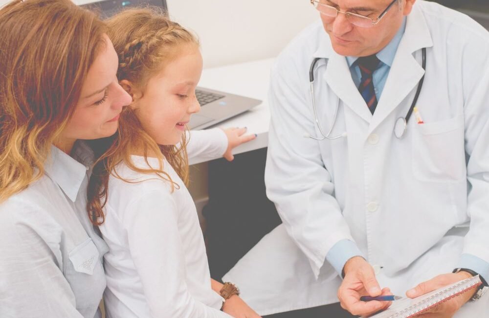 Médico infectologista pediátrico examinando uma criança e orientando os pais sobre doenças bacterianas.
