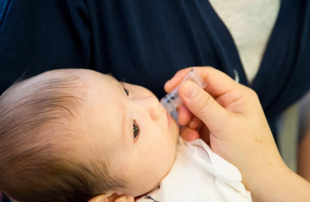 Médico segurando frasco de vacina contra rotavírus, reforçando a importância da imunização infantil.
