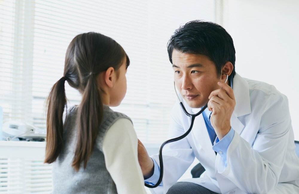 Infectologista pediátrico atendendo criança em consulta com os pais.